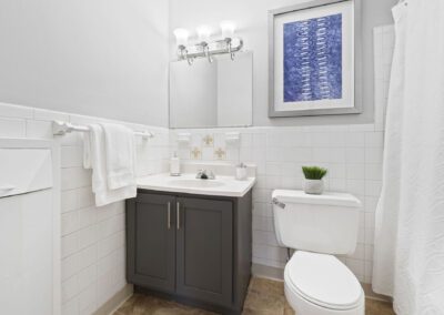 A clean bathroom featuring a toilet, sink, and a decorative shower curtain in a neutral color scheme