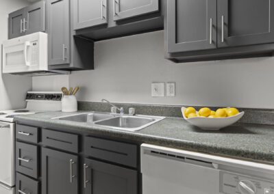 A modern kitchen featuring sleek gray cabinets paired with stylish white appliances and white bowl with lemons on countertop